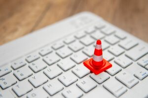 a-miniature-traffic-cone-placed-on-a-computer-keyboard-